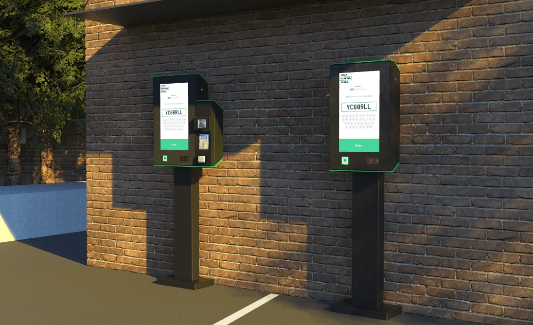 Two Payment kiosks next to a wall in a parking lot